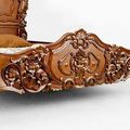 Light brown wood stained detail on the footboard of rococo bed