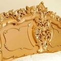 Headboard detail and wood carving accent of gold painted rococo bed