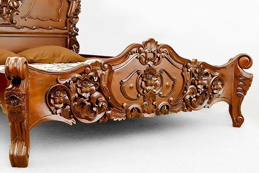 Light brown wood stained detail on the footboard of rococo bed