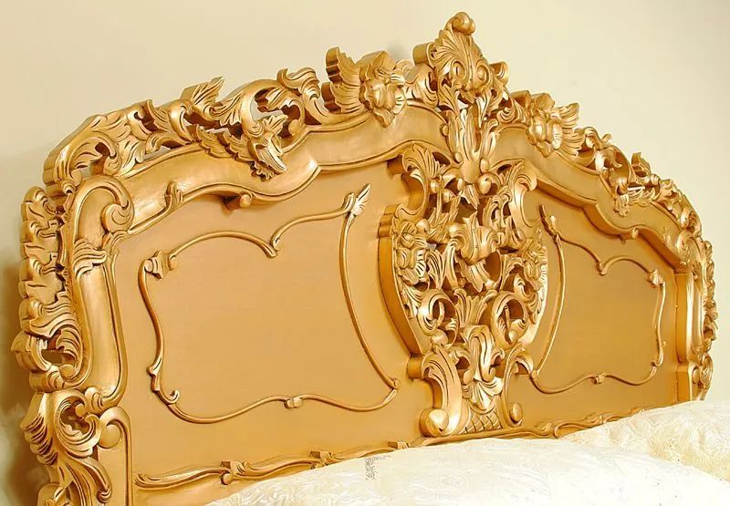 Headboard detail and wood carving accent of gold painted rococo bed